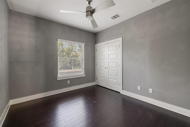 unfurnished bedroom with dark wood-type flooring, a ceiling fan, and baseboards