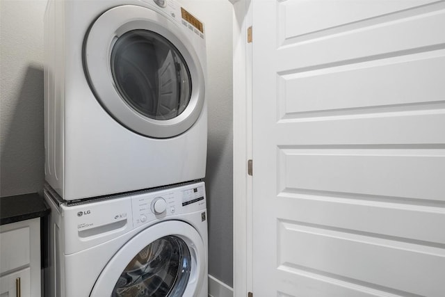 laundry area with stacked washer / dryer and cabinet space