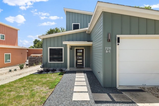 entrance to property featuring board and batten siding, an attached garage, and fence