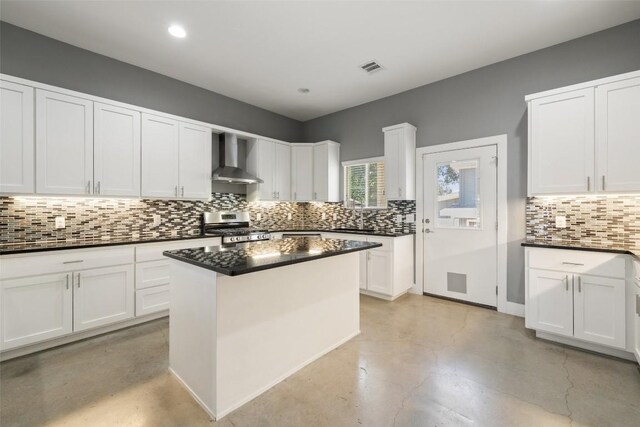 kitchen with white cabinetry, a kitchen island, wall chimney range hood, and stainless steel stove