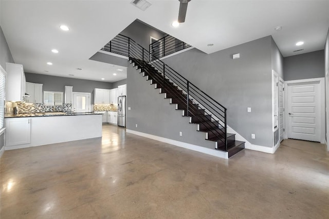 unfurnished living room featuring baseboards, finished concrete floors, visible vents, and stairs