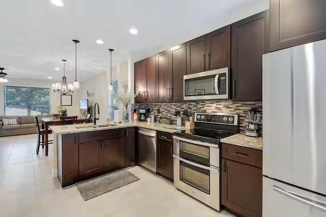 kitchen featuring ceiling fan with notable chandelier, sink, hanging light fixtures, kitchen peninsula, and stainless steel appliances