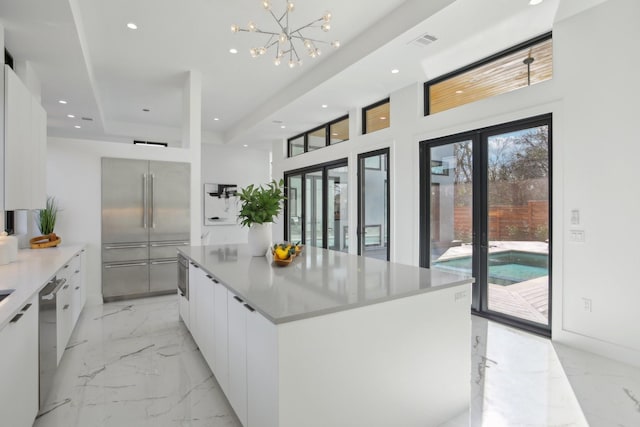 kitchen with a large island, white cabinetry, an inviting chandelier, stainless steel appliances, and french doors