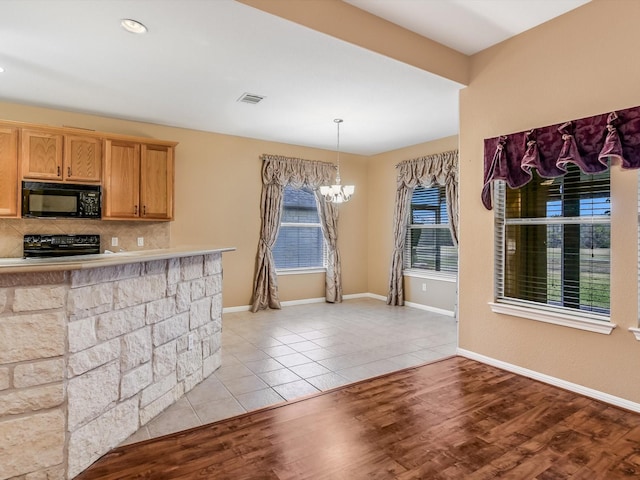 kitchen with pendant lighting, black appliances, tasteful backsplash, a notable chandelier, and light tile patterned flooring