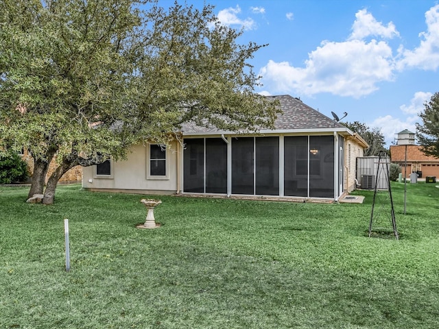 rear view of property with a lawn, a sunroom, and central AC