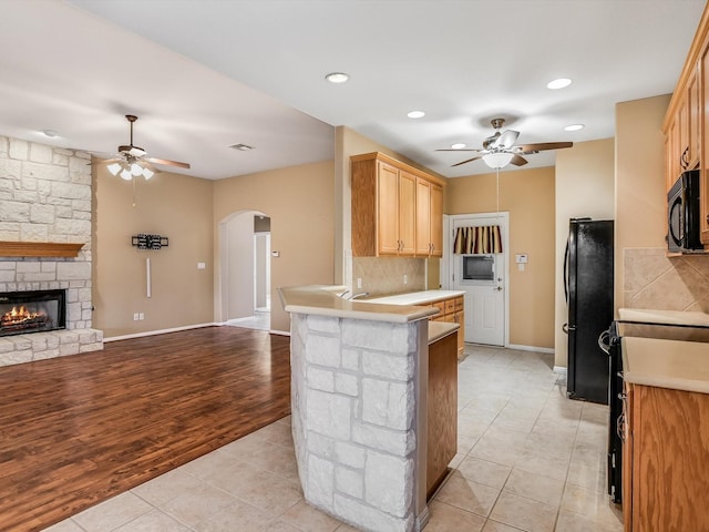 kitchen with black appliances, decorative backsplash, kitchen peninsula, and light tile patterned floors