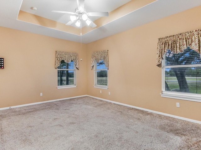 empty room with carpet, ceiling fan, and a raised ceiling