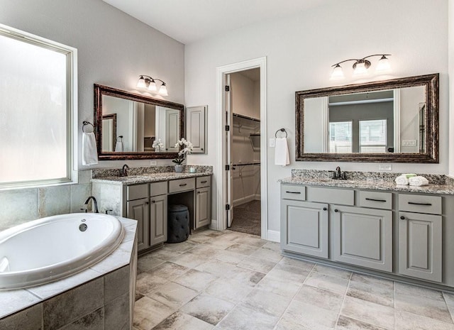 bathroom featuring plenty of natural light, vanity, and a relaxing tiled tub