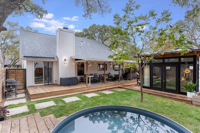 rear view of house featuring french doors, a yard, and a swimming pool side deck