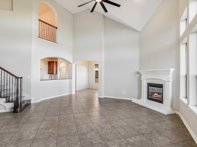 unfurnished living room with a ceiling fan, a glass covered fireplace, and baseboards