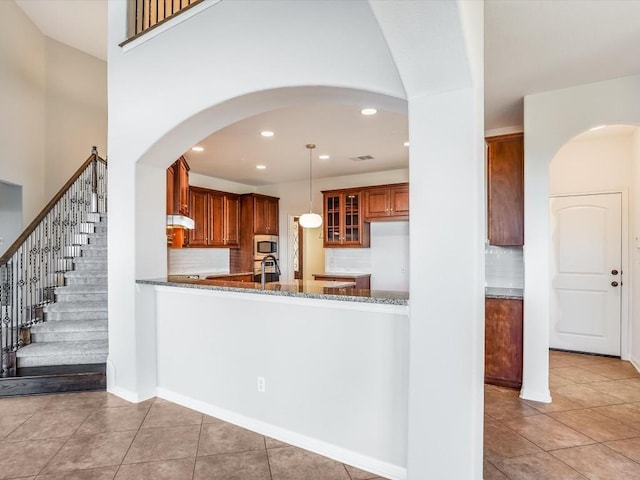 kitchen with dark stone counters, stainless steel microwave, tile patterned flooring, and visible vents