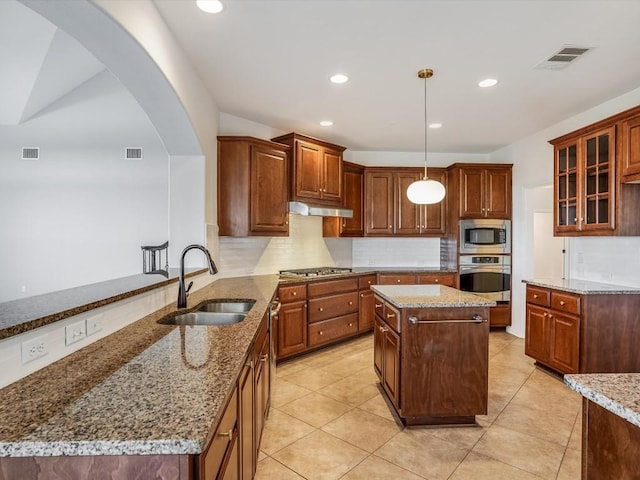 kitchen with tasteful backsplash, visible vents, appliances with stainless steel finishes, under cabinet range hood, and a sink