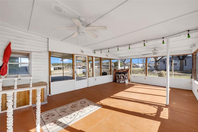 unfurnished sunroom featuring ceiling fan and a healthy amount of sunlight