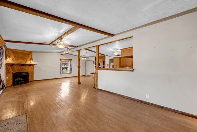 unfurnished living room with vaulted ceiling with beams, ceiling fan, light wood-type flooring, a textured ceiling, and a large fireplace