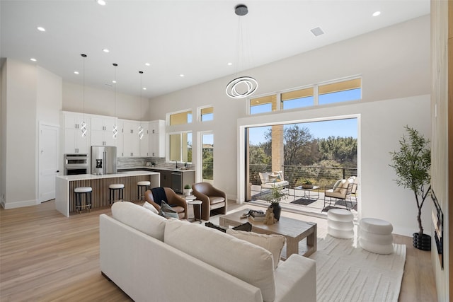 living room with sink, a high ceiling, and light wood-type flooring