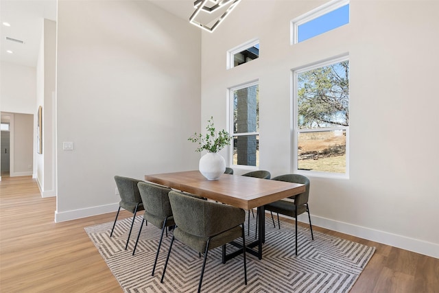 dining space featuring a high ceiling and light wood-type flooring