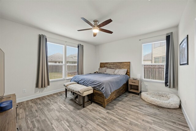 bedroom featuring multiple windows, light hardwood / wood-style flooring, and ceiling fan