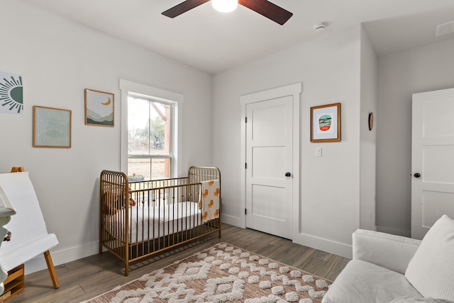 bedroom featuring ceiling fan, a crib, and hardwood / wood-style flooring