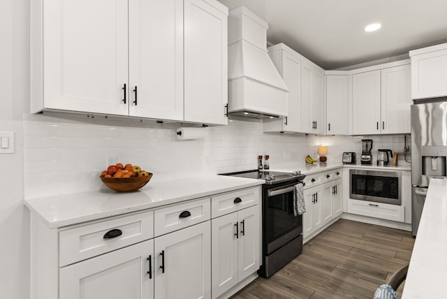 kitchen with electric range, custom exhaust hood, white cabinetry, and stainless steel fridge with ice dispenser