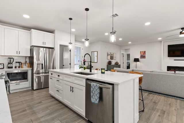 kitchen featuring appliances with stainless steel finishes, white cabinetry, pendant lighting, and sink