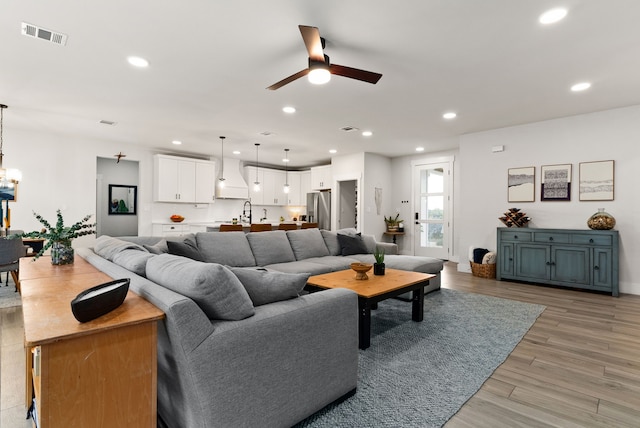 living room with ceiling fan, light hardwood / wood-style flooring, and sink