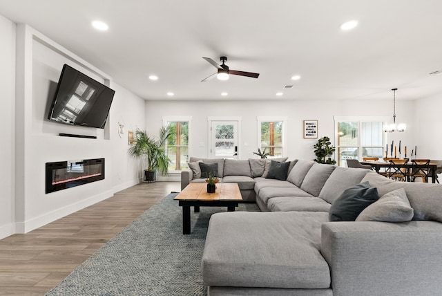 living room featuring light hardwood / wood-style floors and ceiling fan with notable chandelier