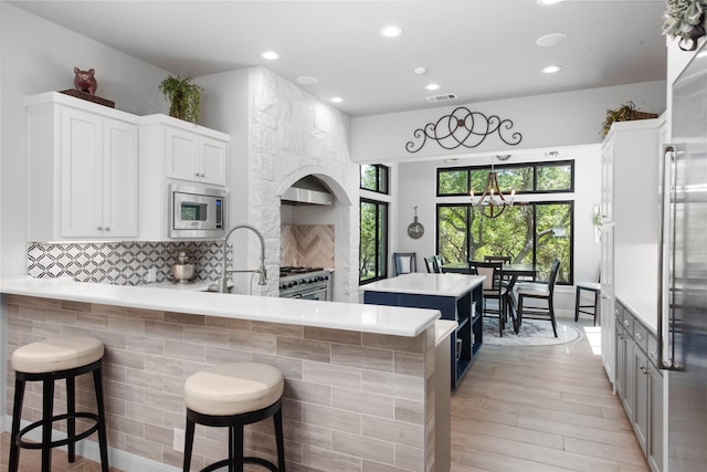 kitchen featuring a breakfast bar area, kitchen peninsula, white cabinetry, and appliances with stainless steel finishes