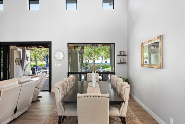 dining space with a high ceiling and hardwood / wood-style flooring