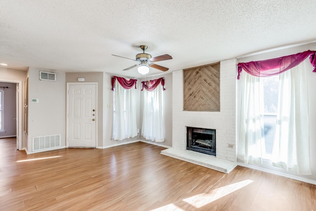 unfurnished living room featuring a textured ceiling, ceiling fan, a healthy amount of sunlight, and wood-type flooring