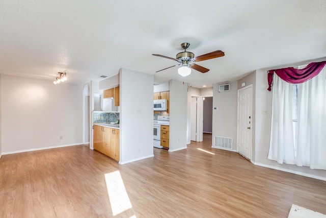 unfurnished living room with ceiling fan, sink, a textured ceiling, and light hardwood / wood-style flooring