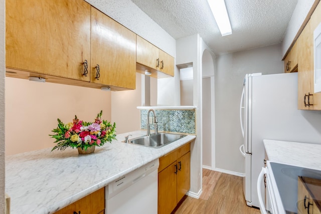 kitchen featuring white appliances, a textured ceiling, light hardwood / wood-style floors, sink, and decorative backsplash