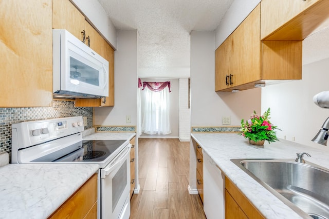 kitchen with tasteful backsplash, light hardwood / wood-style floors, sink, white appliances, and a textured ceiling