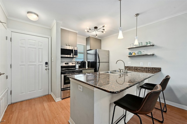 kitchen featuring kitchen peninsula, a kitchen breakfast bar, stainless steel appliances, sink, and hanging light fixtures