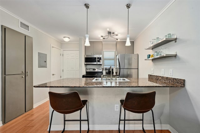 kitchen featuring sink, kitchen peninsula, crown molding, pendant lighting, and appliances with stainless steel finishes