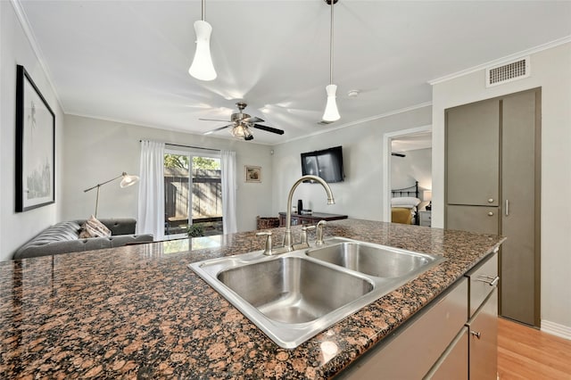 kitchen with crown molding, dark stone countertops, sink, and hanging light fixtures