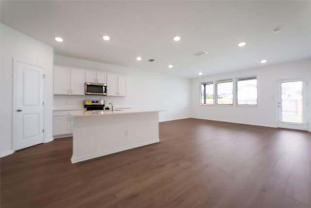 kitchen featuring an island with sink, dark hardwood / wood-style flooring, white cabinets, stove, and sink