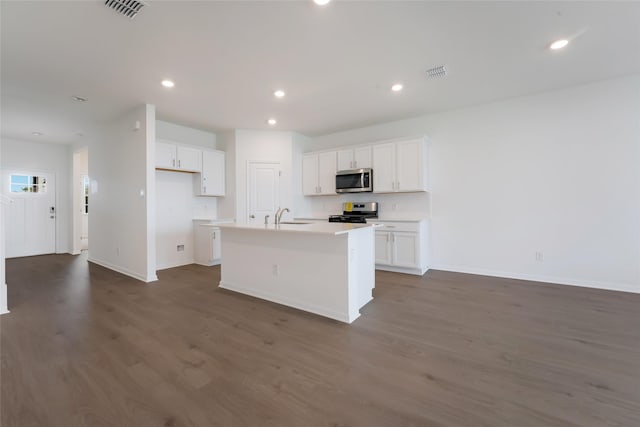 kitchen with an island with sink, stainless steel appliances, white cabinets, and dark hardwood / wood-style floors