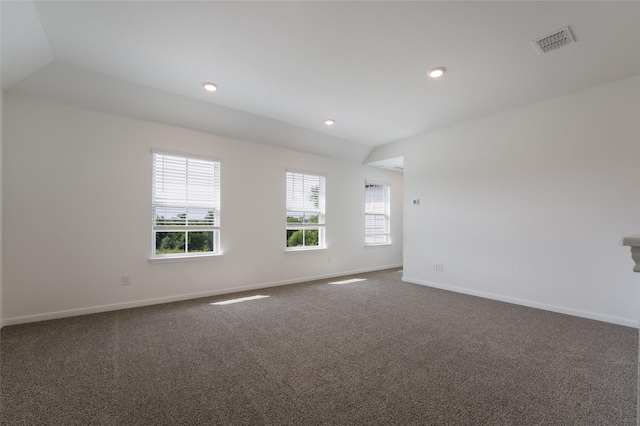 carpeted empty room featuring a wealth of natural light and vaulted ceiling