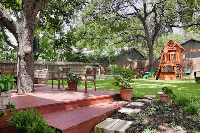 exterior space with a fenced backyard, a playground, and a wooden deck