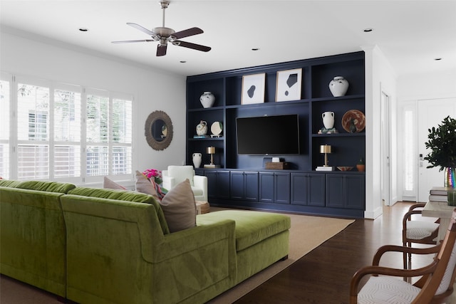 living area with ceiling fan, built in shelves, crown molding, and wood finished floors