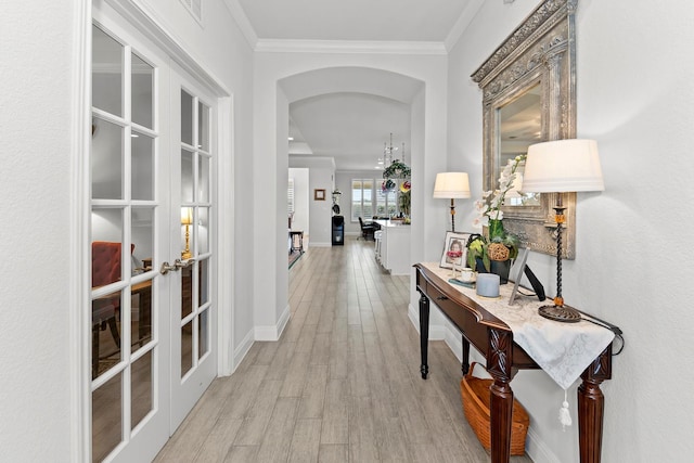 corridor with french doors, ornamental molding, and light hardwood / wood-style flooring