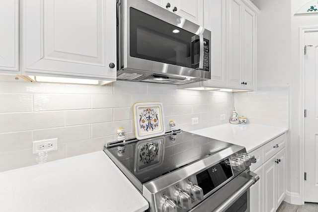 kitchen featuring white cabinets, stainless steel appliances, and backsplash