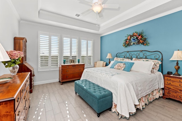 bedroom featuring ceiling fan, a tray ceiling, crown molding, and light hardwood / wood-style flooring