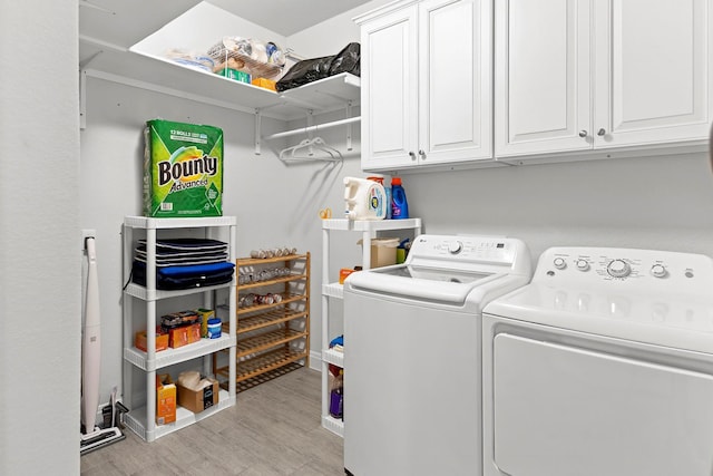 laundry area featuring cabinets, washing machine and clothes dryer, and light hardwood / wood-style floors