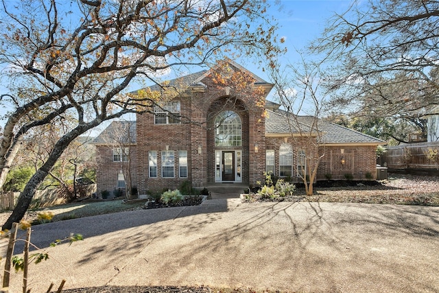 traditional-style home with cooling unit, brick siding, and fence