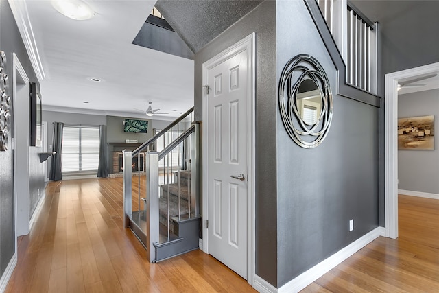 hallway with lofted ceiling, light wood-type flooring, and crown molding