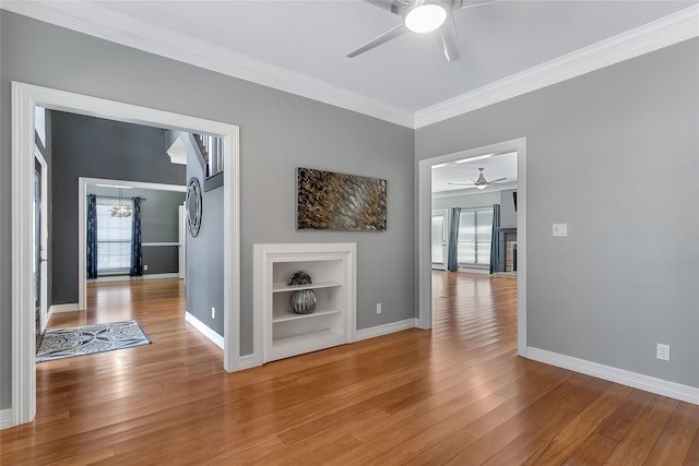 hallway featuring baseboards, hardwood / wood-style floors, built in features, and crown molding