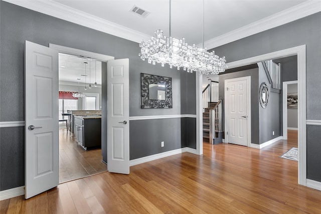 unfurnished dining area with visible vents, crown molding, stairway, and wood finished floors