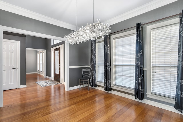 unfurnished dining area with wood-type flooring, ornamental molding, a wealth of natural light, and a notable chandelier