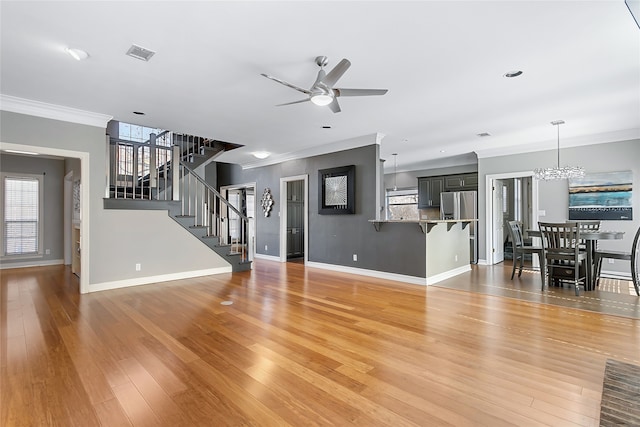 unfurnished living room featuring crown molding, visible vents, light wood-style flooring, baseboards, and stairs